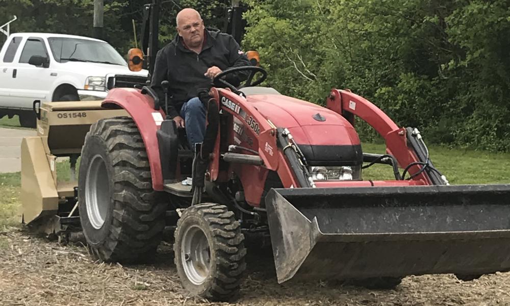 Photo of man on tractor planting pollinator plot