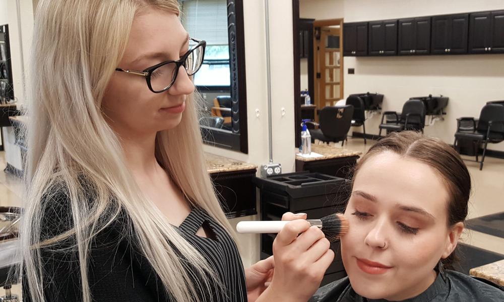 Student applying makeup with a brush