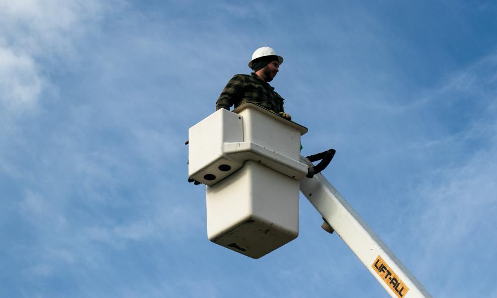 Student in bucket truck against a blue sky
